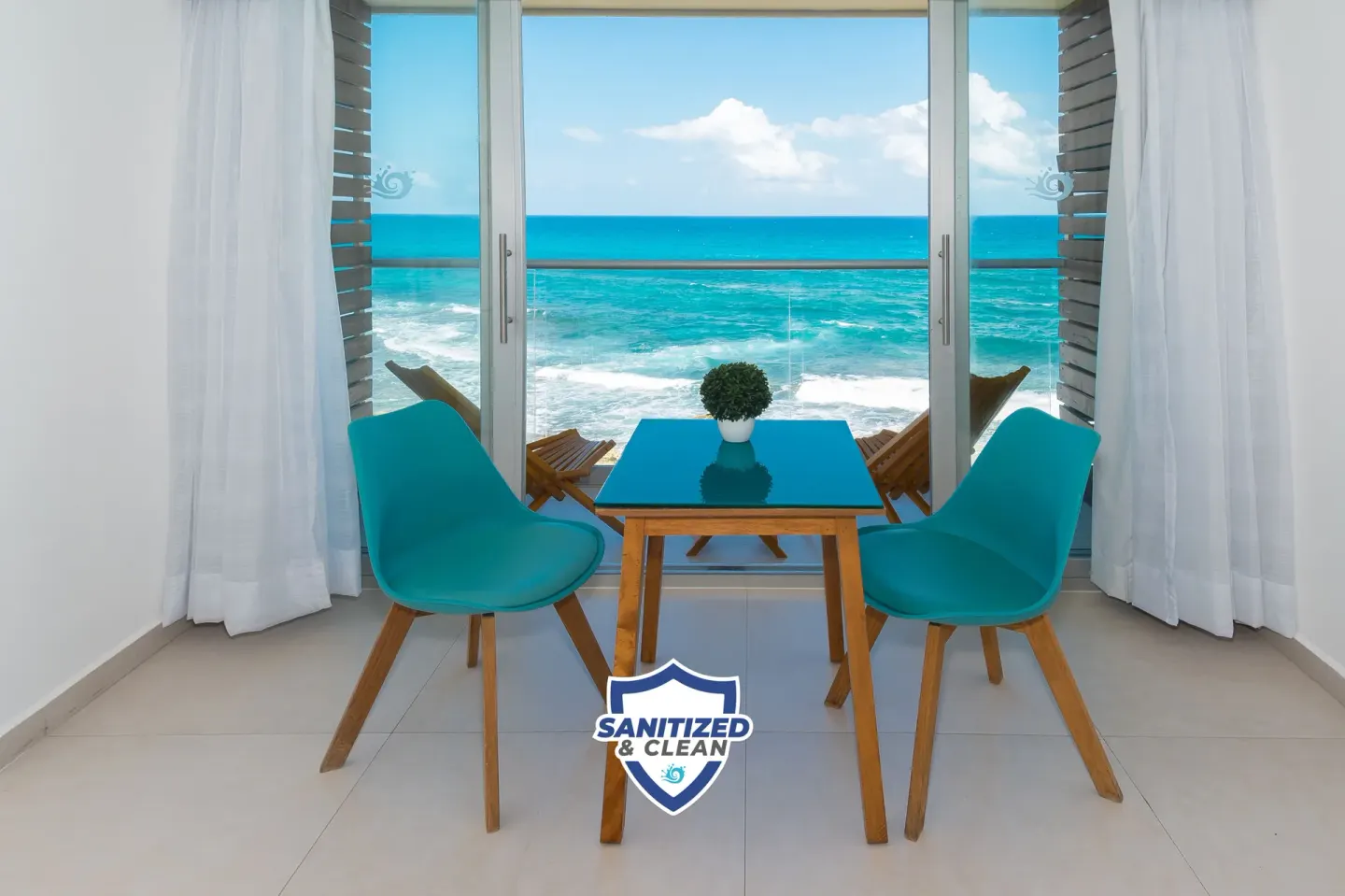 Ocean-view sitting area in a Deluxe Room at Mia Reef Isla Mujeres with turquoise water beyond the glass doors.