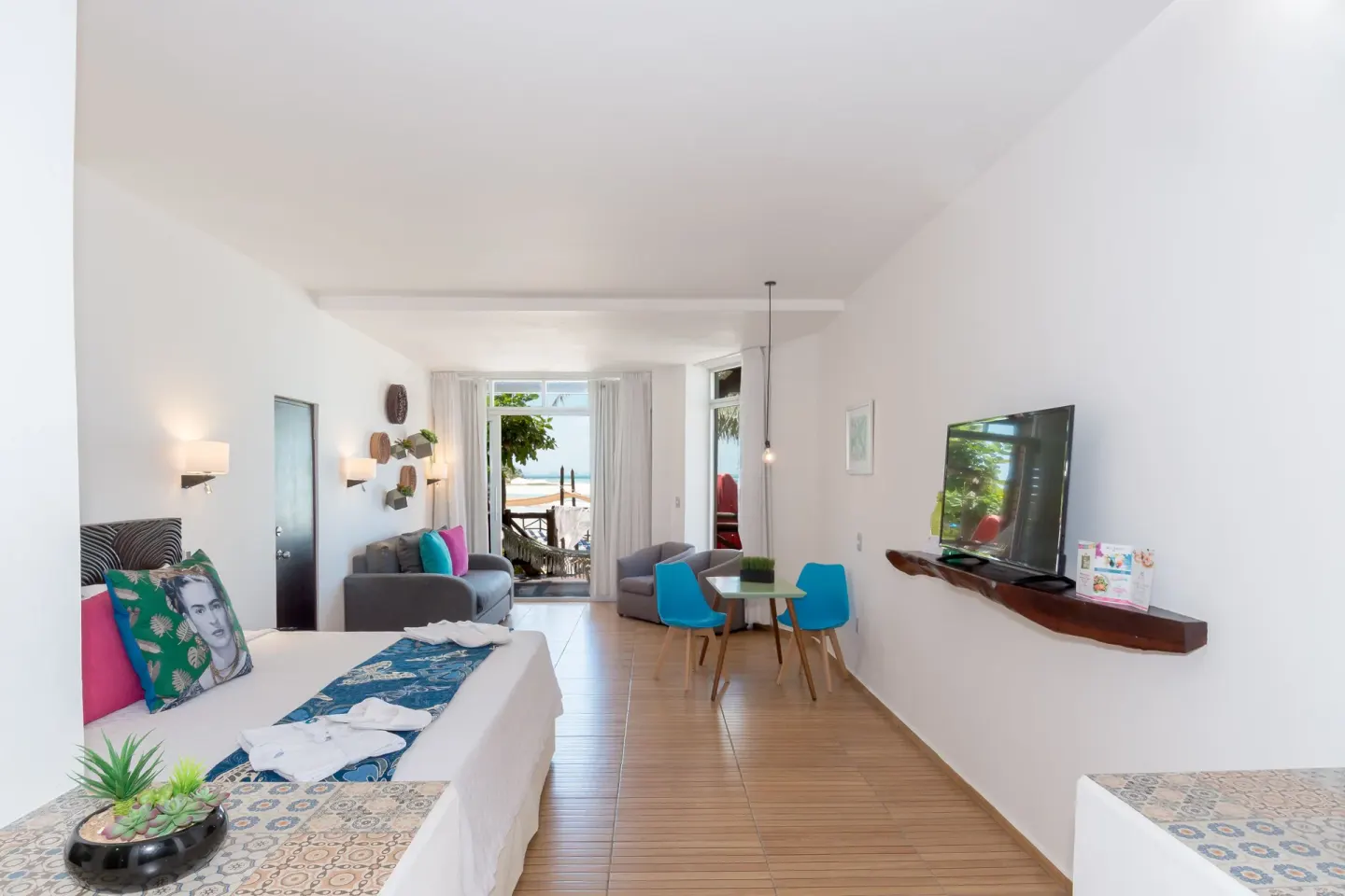 Deluxe Villa Ocean Front Suite with bed, sofa, TV and balcony view at Mia Reef Isla Mujeres.