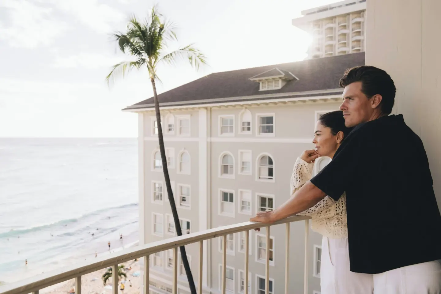 Couple looking over the beach from a balcony at Moana Surfrider, A Westin Resort & Spa.