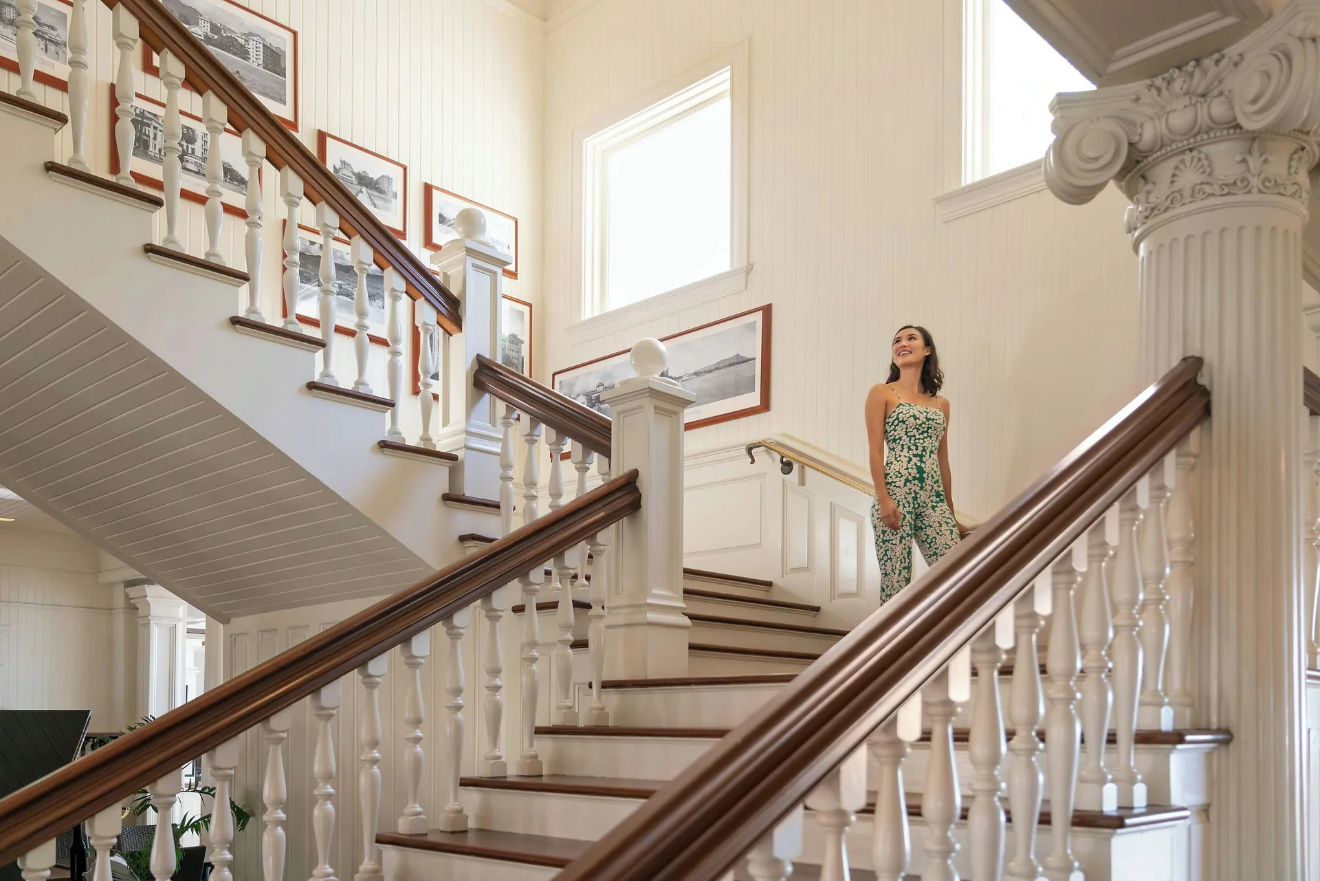 Grand staircase with white railings and historic photos at Moana Surfrider, A Westin Resort & Spa.