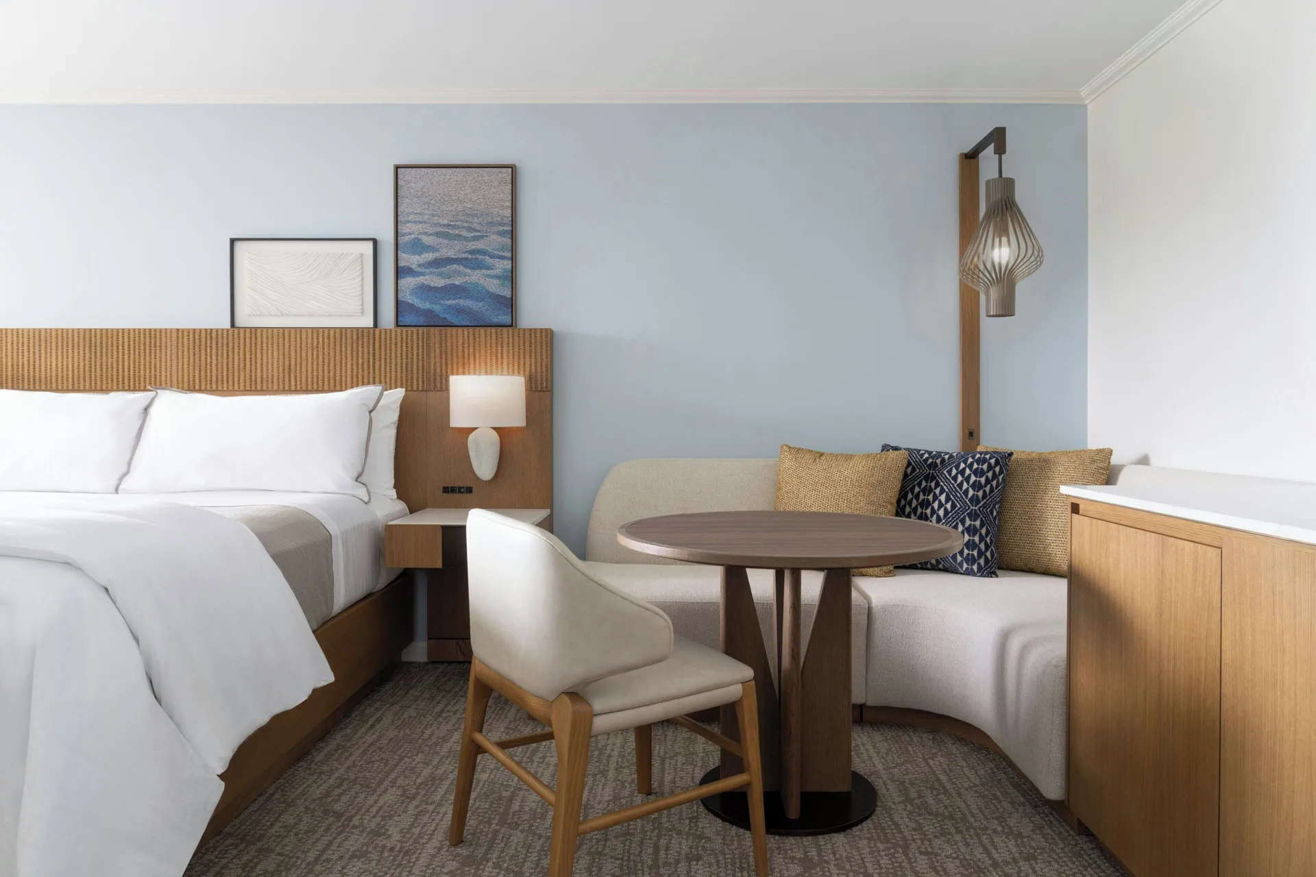 Guest room with king bed, sofa nook and round table at Moana Surfrider, A Westin Resort & Spa.