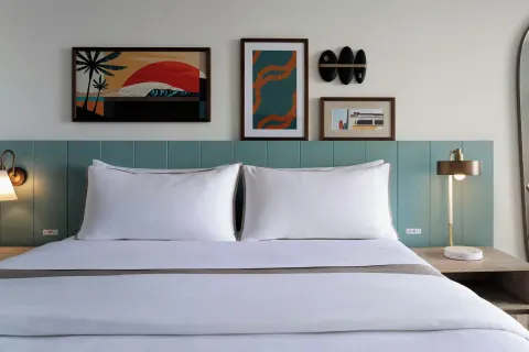 Guest room king bed with teal headboard at Moana Surfrider, A Westin Resort & Spa.