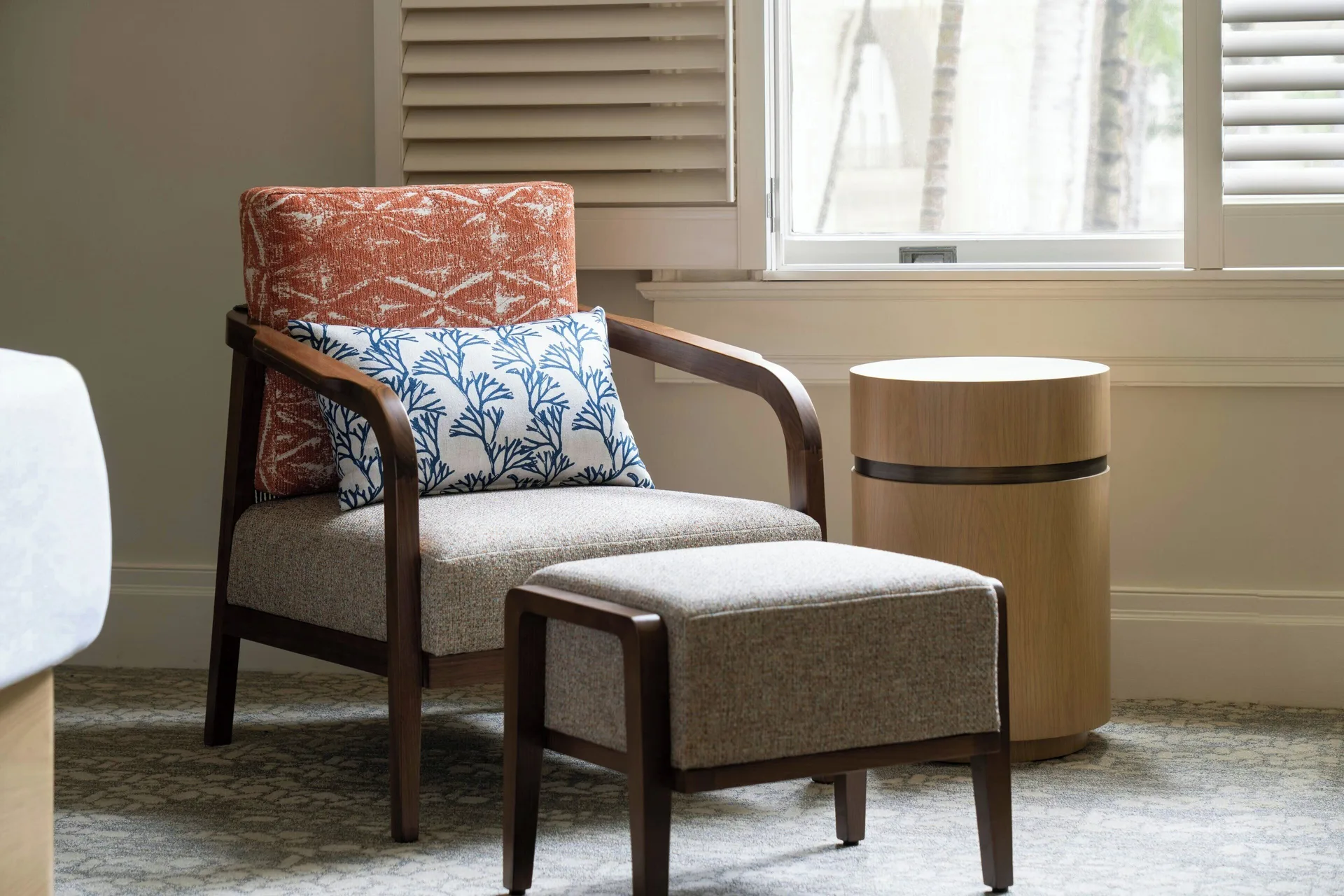 Guest room lounge chair and ottoman by a window at Moana Surfrider, A Westin Resort & Spa.