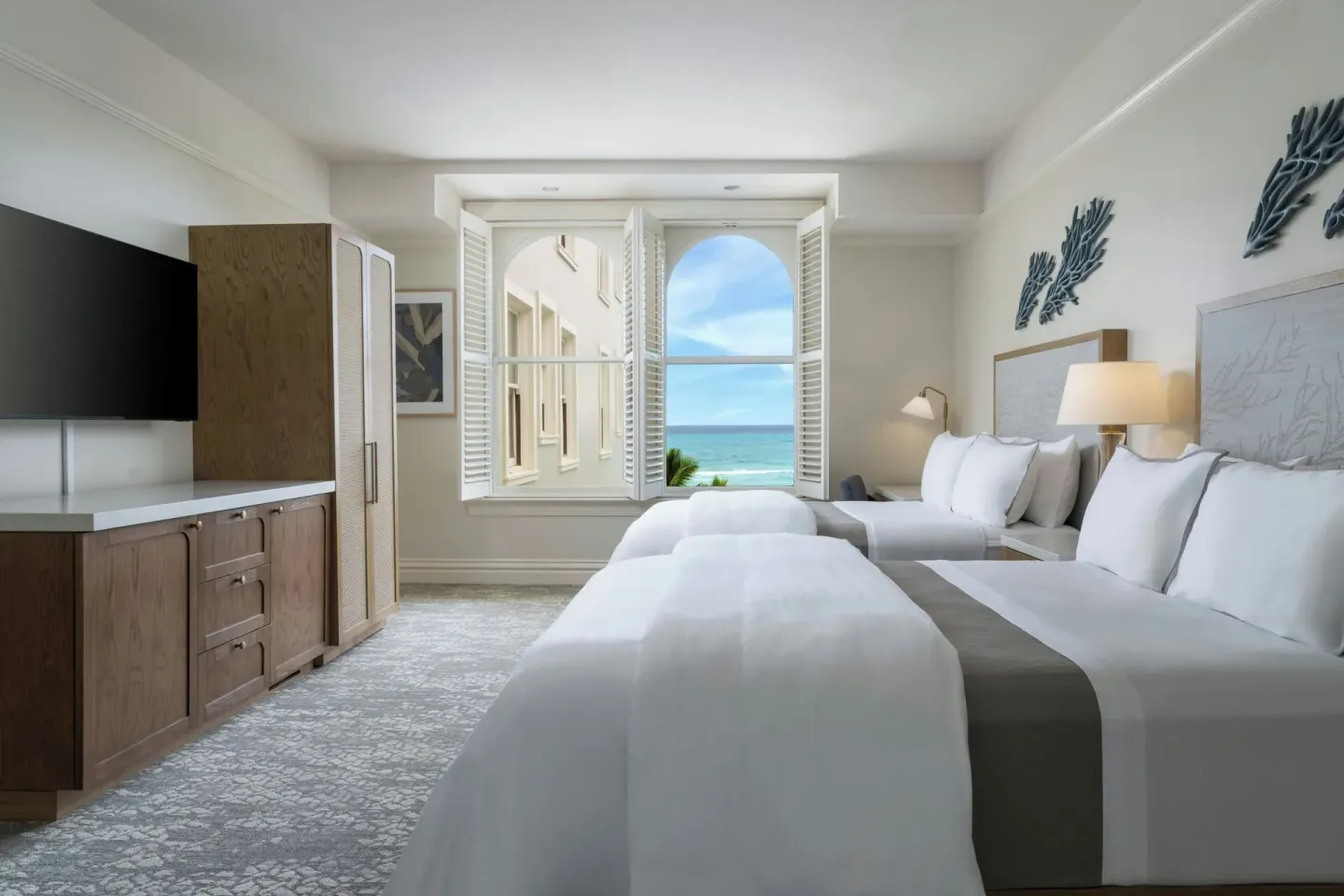 Two-bed guest room with shuttered ocean-view window at Moana Surfrider, A Westin Resort & Spa.