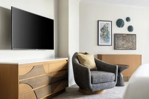 Guest room TV, dresser, and lounge chair at Moana Surfrider, A Westin Resort & Spa.