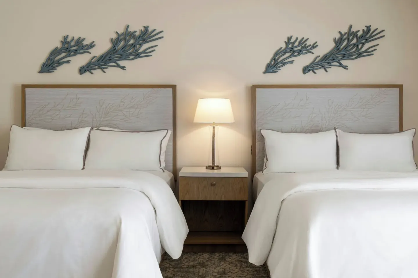 Two beds with coral wall decor and a shared nightstand at Moana Surfrider, A Westin Resort & Spa.