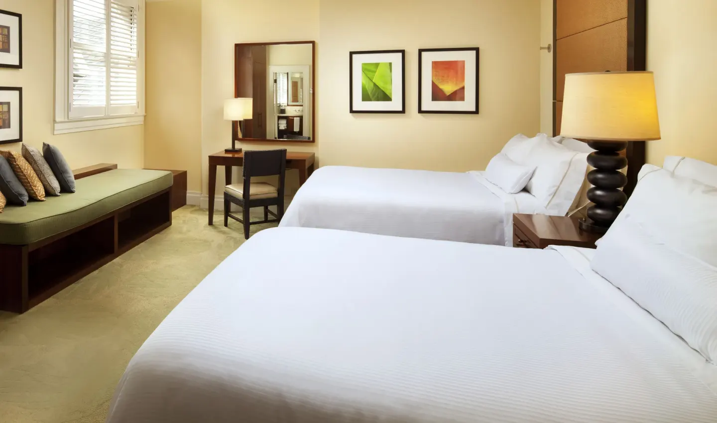 Two-bed guest room with window bench at Moana Surfrider, A Westin Resort & Spa.