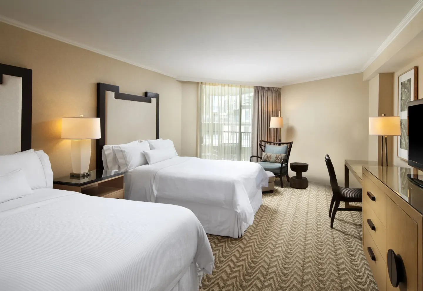 Two-bed guest room with seating area at Moana Surfrider, A Westin Resort & Spa.