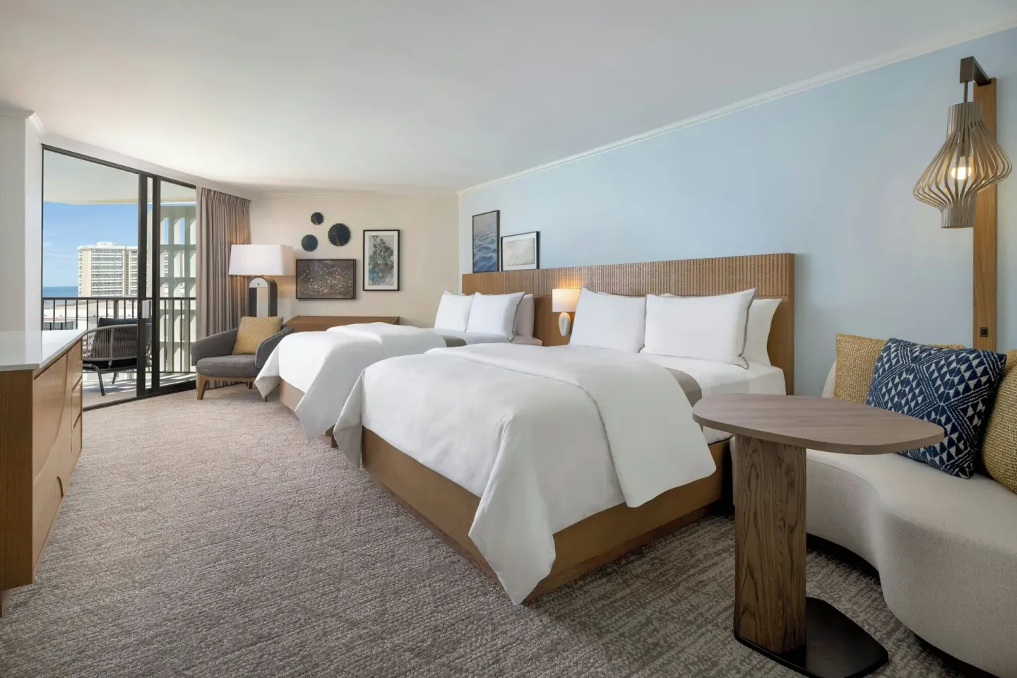 Two-bed guest room with sitting area at Moana Surfrider, A Westin Resort & Spa.