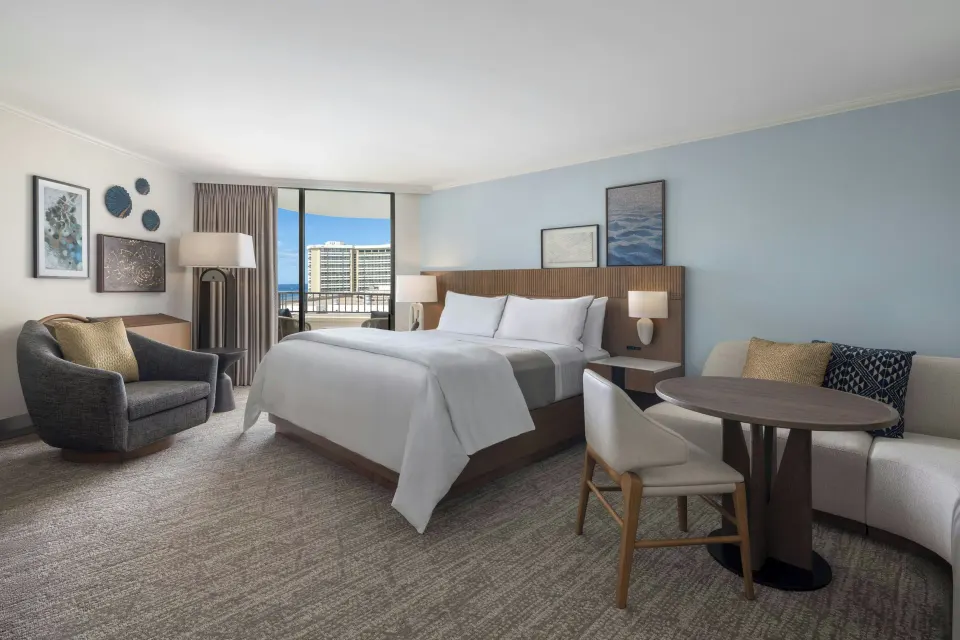 King bed guest room with sofa and balcony at Moana Surfrider, A Westin Resort & Spa.