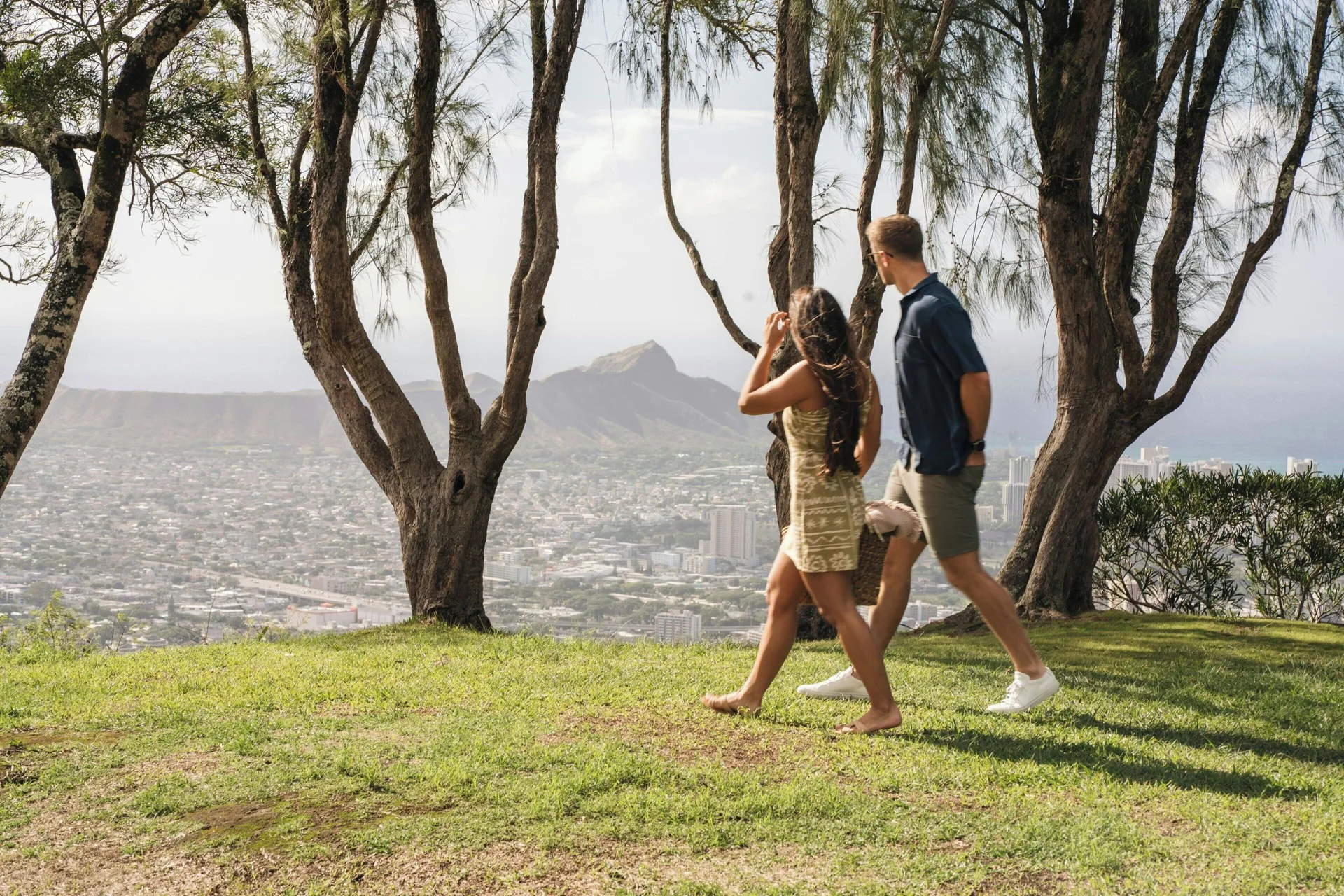 Couple walks under trees with Honolulu views near Moana Surfrider, A Westin Resort & Spa.