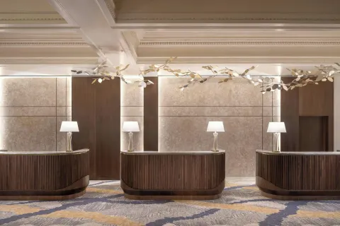 Three wood reception desks in the lobby at Moana Surfrider, A Westin Resort & Spa.