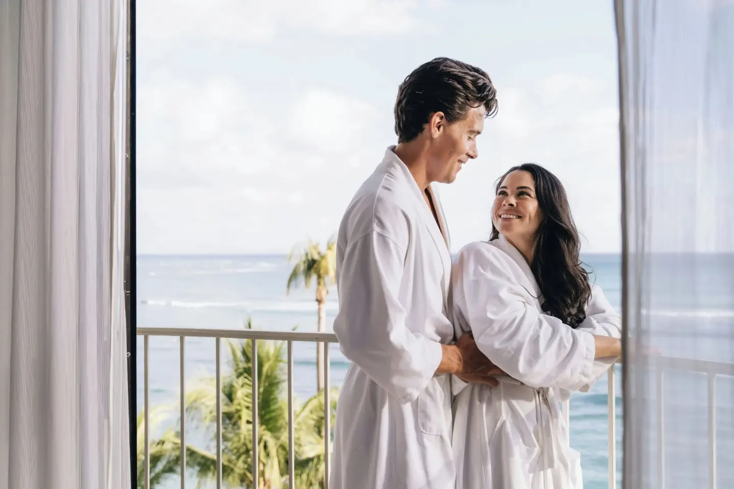 Couple in robes on an ocean-view balcony at Moana Surfrider, A Westin Resort & Spa.