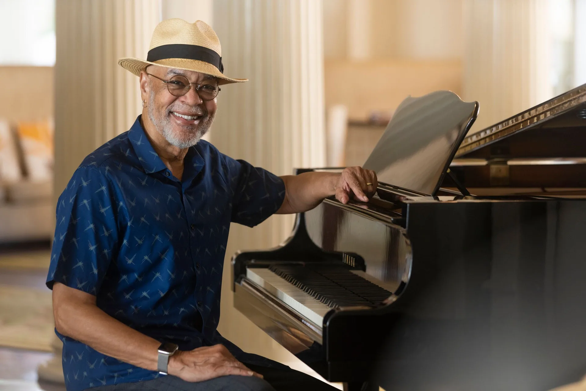 A smiling pianist beside a grand piano at Moana Surfrider, A Westin Resort & Spa.