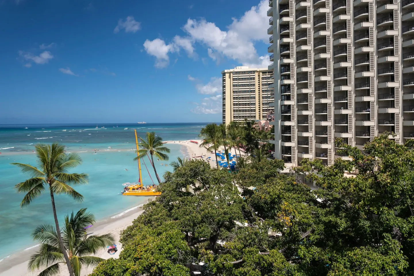 Waikiki Beach, palm trees, and resort tower at Moana Surfrider, A Westin Resort & Spa.