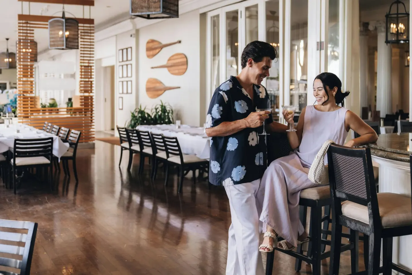 Guests toast cocktails at a bar inside Moana Surfrider, A Westin Resort & Spa.