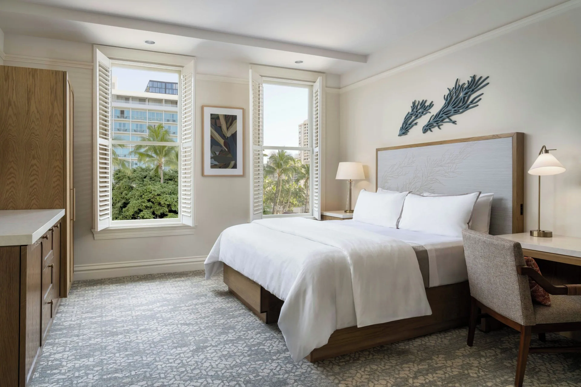 Banyan Deluxe Room king bed with desks, armchairs, and tall windows at Moana Surfrider, A Westin Resort & Spa.