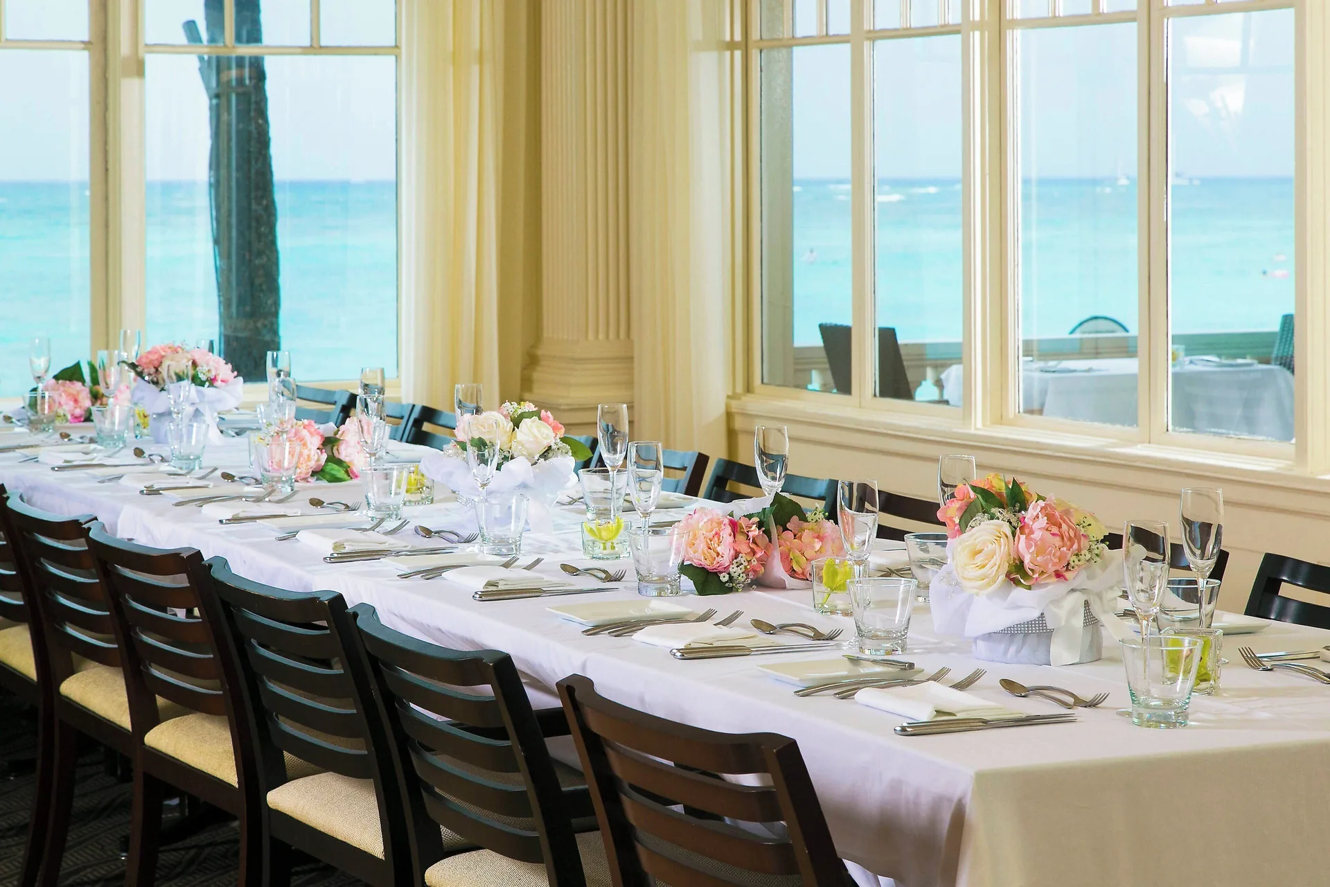 Long oceanfront event table set with flowers at Moana Surfrider, A Westin Resort & Spa.