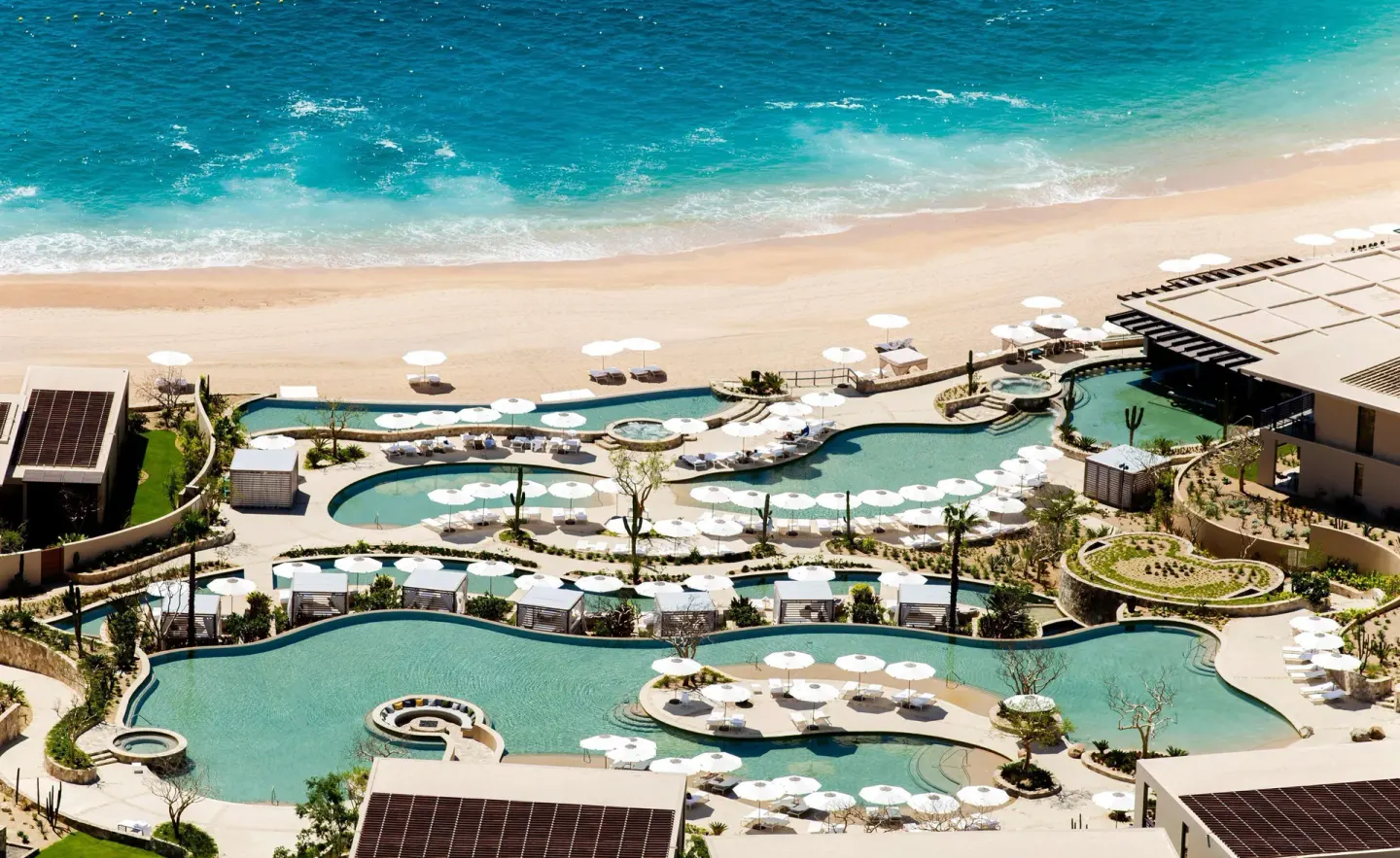 Aerial view of beachfront pools and white umbrellas at Montage Los Cabos.