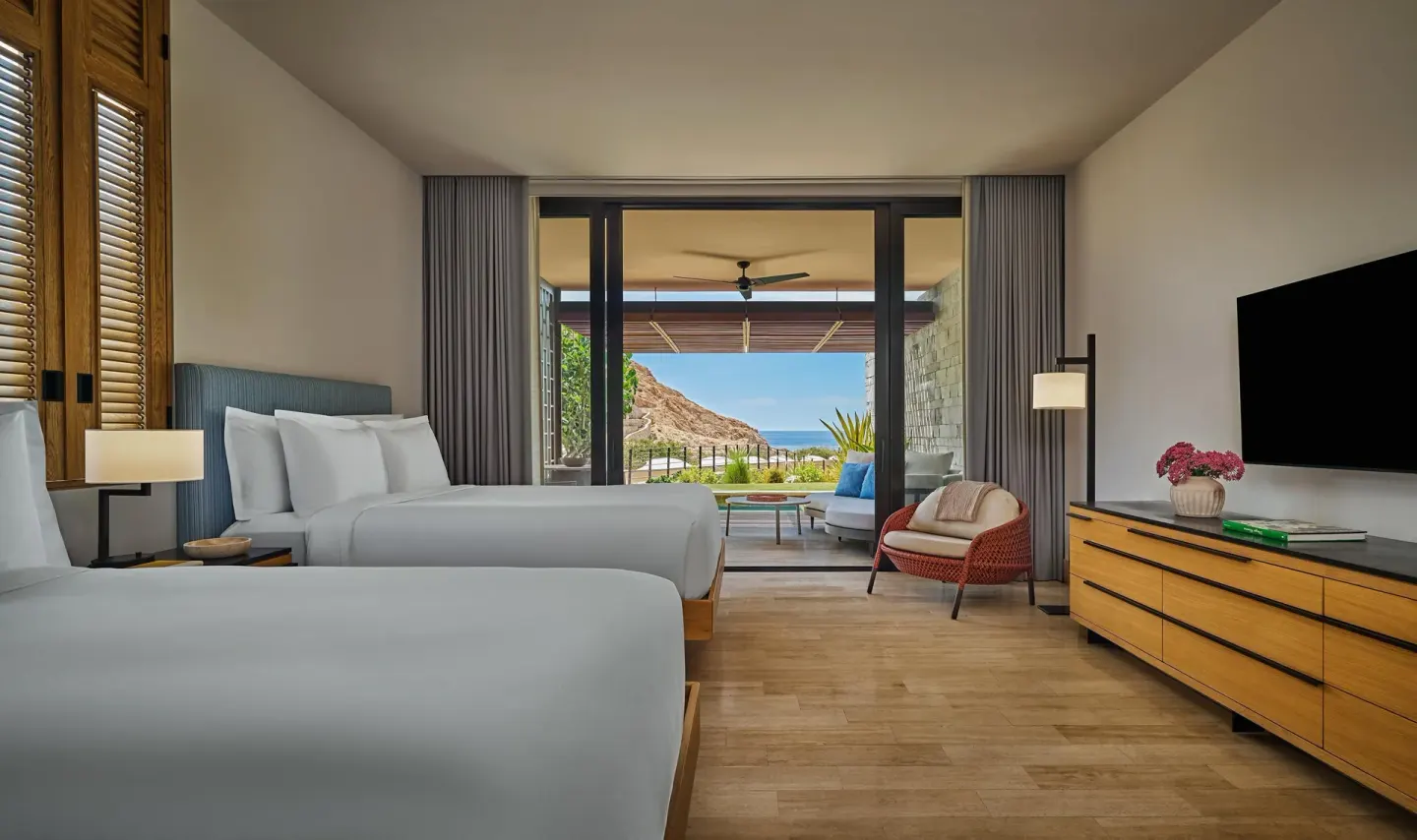 Two-bed guest room with TV, terrace, and coastal hillside view at Montage Los Cabos.