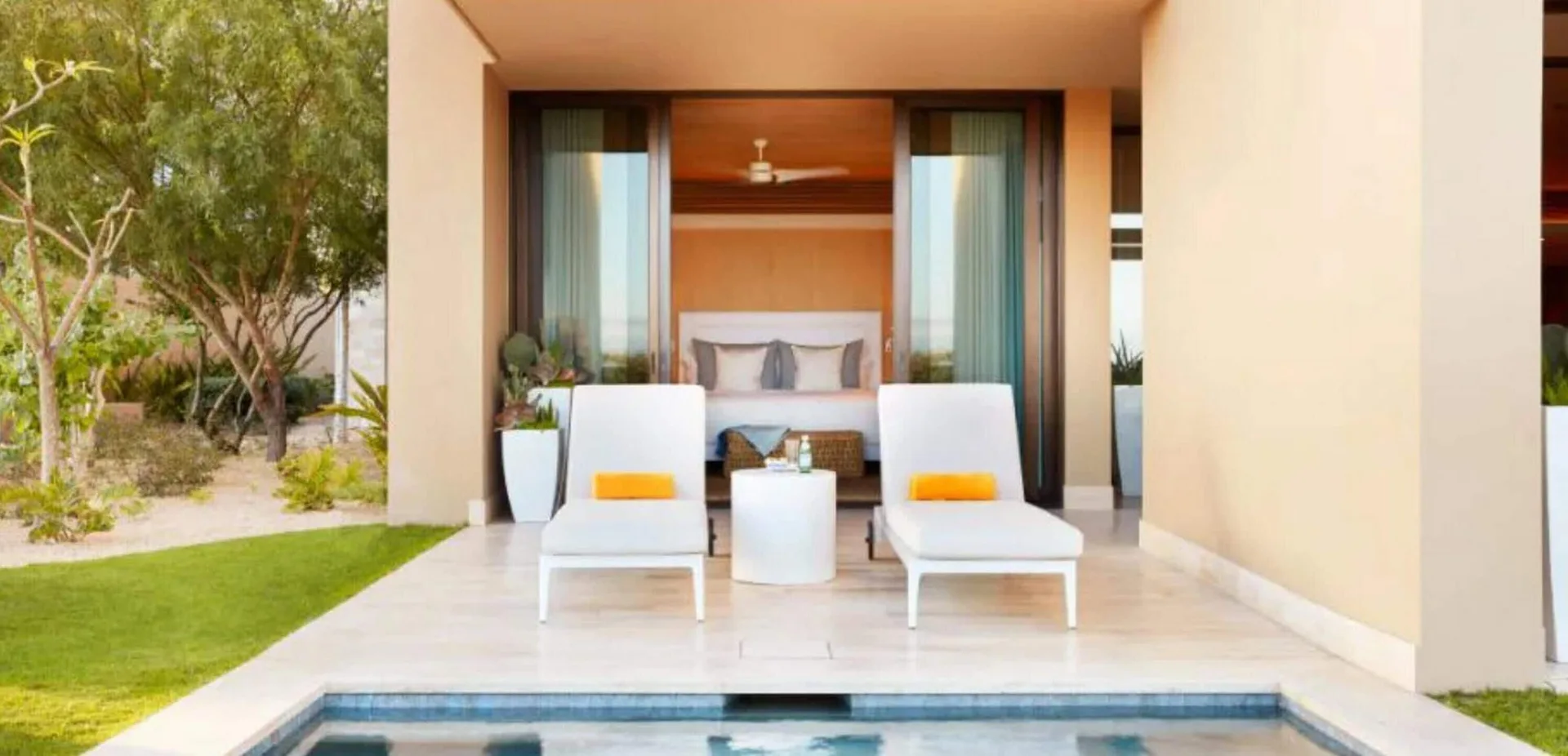 Patio with two chaise lounges, a plunge pool, and bedroom beyond at Montage Los Cabos.