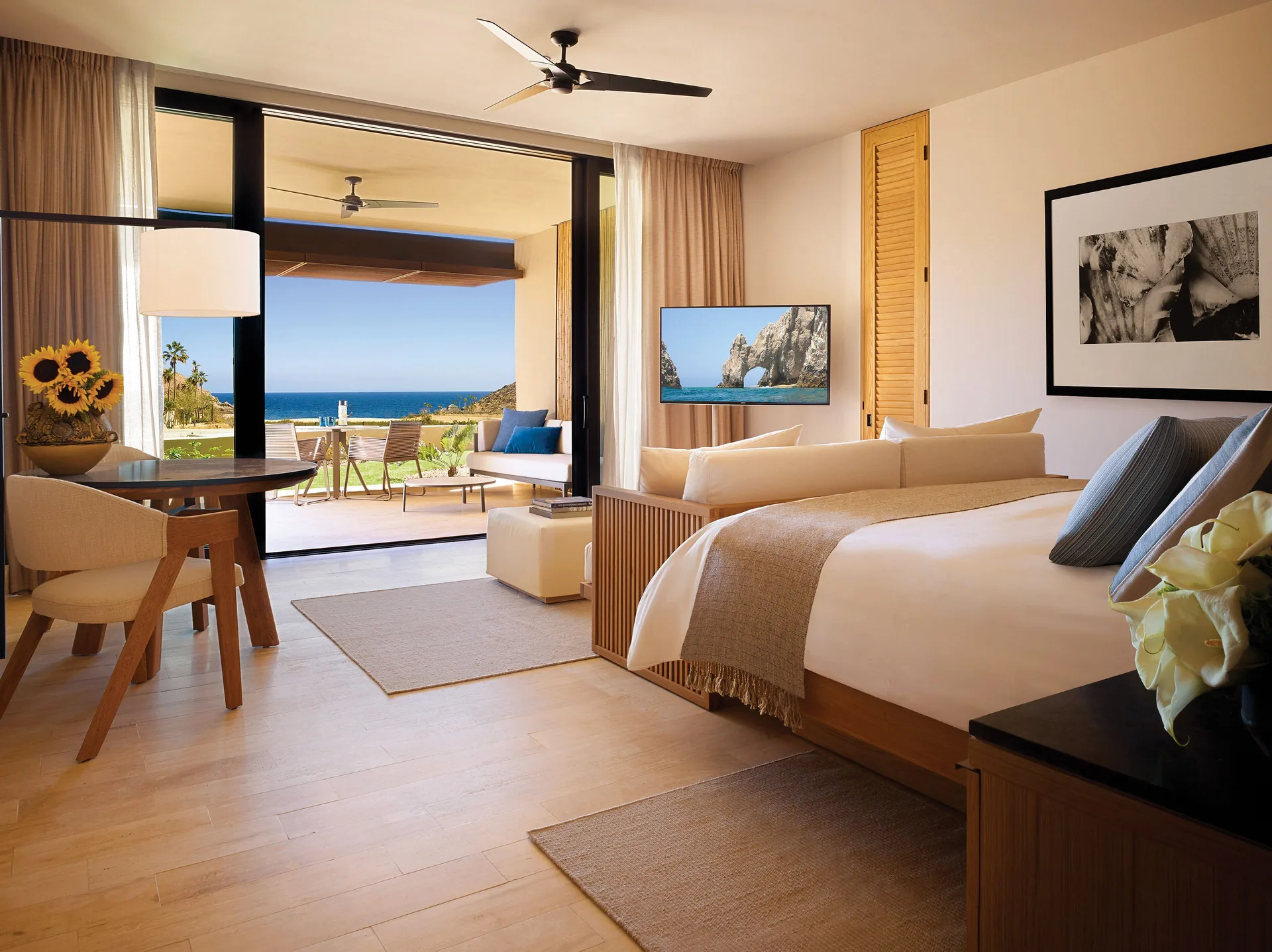 Guest room with a king bed, dining table, sitting area, and ocean-facing terrace at Montage Los Cabos.