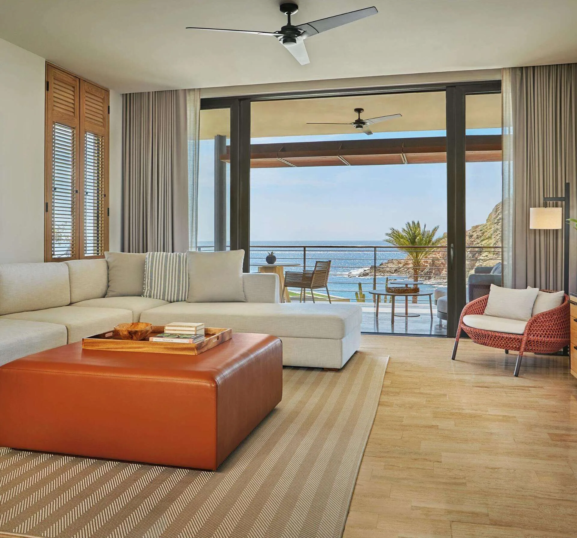 Living room with sectional sofa, leather ottoman, and ocean-view balcony at Montage Los Cabos.