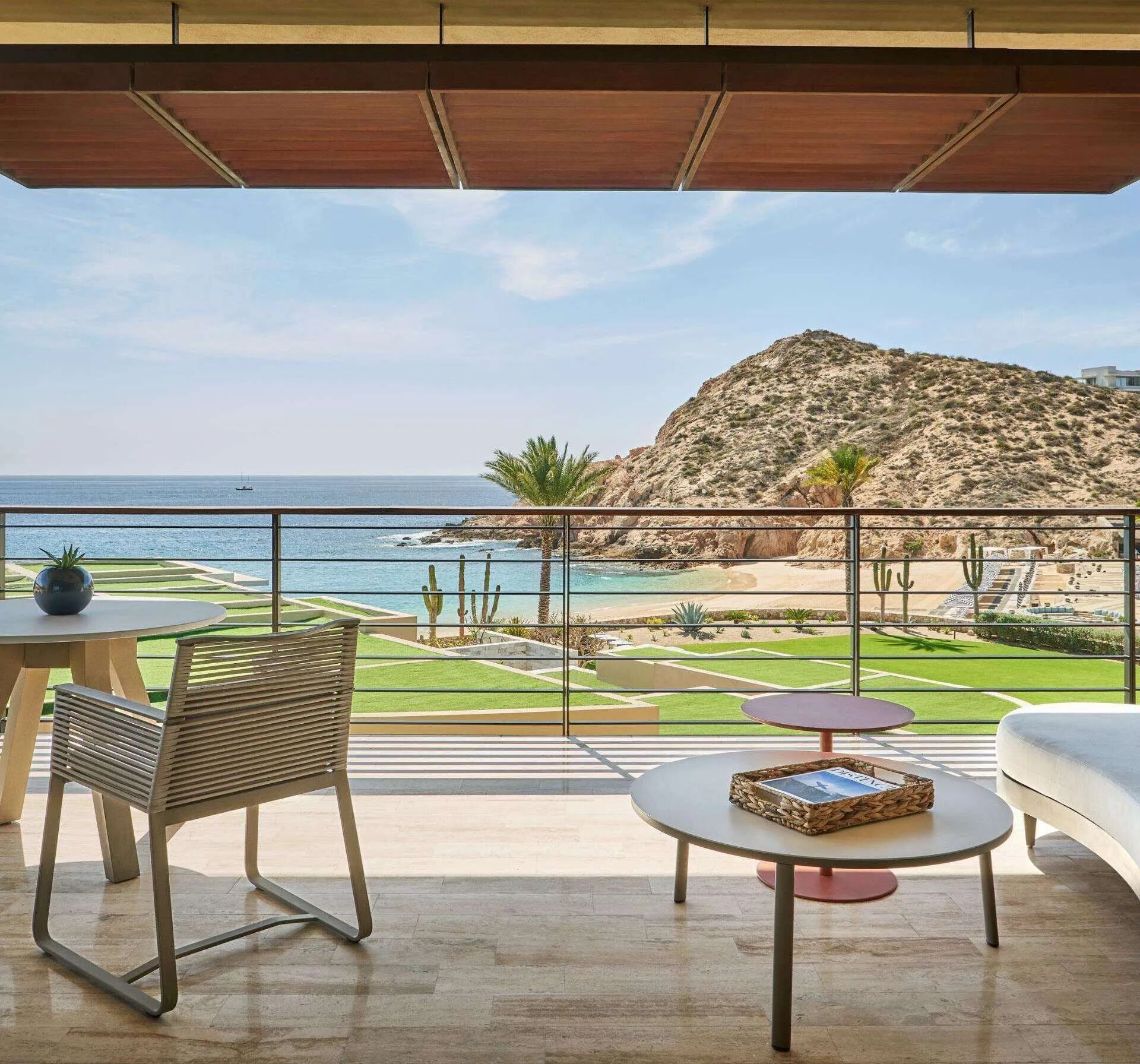 Covered terrace with seating and a view of the beach, bay, and rocky hillside at Montage Los Cabos.