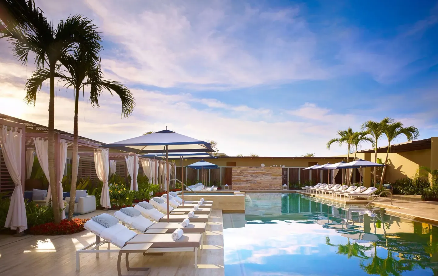 Pool deck with loungers, umbrellas, cabanas, and palm trees at Montage Los Cabos.