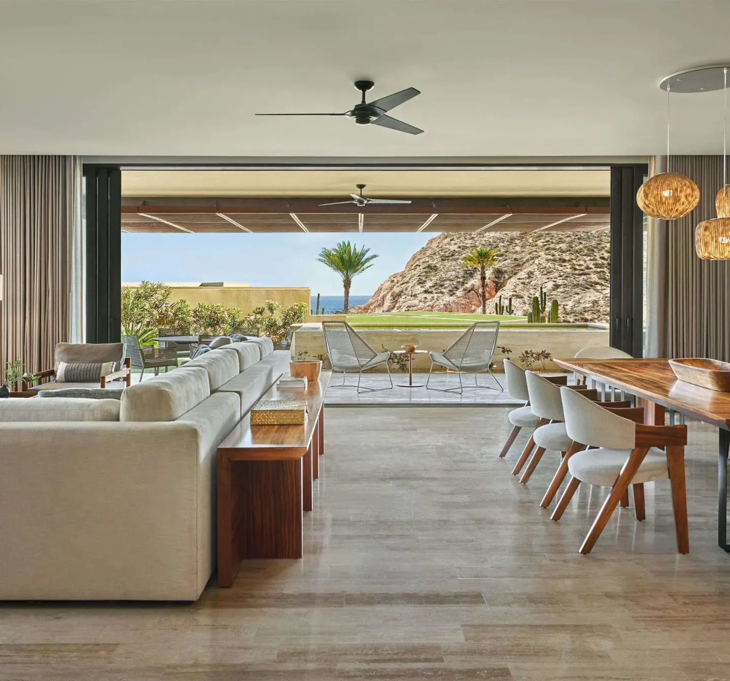 Open living and dining room with terrace seating and hillside view at Montage Los Cabos.