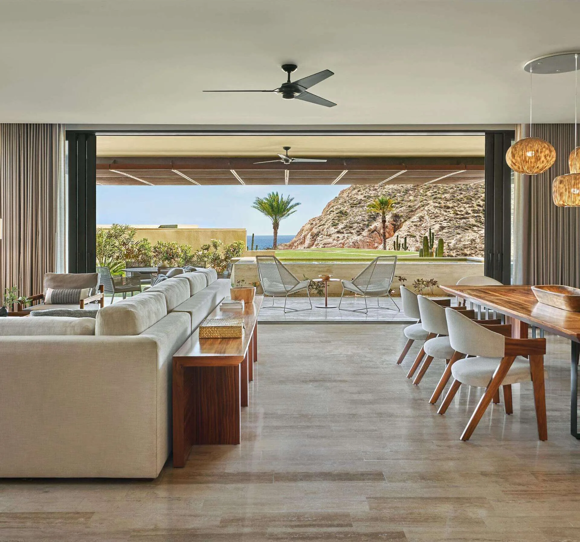 Open living and dining room with terrace seating and hillside view at Montage Los Cabos.