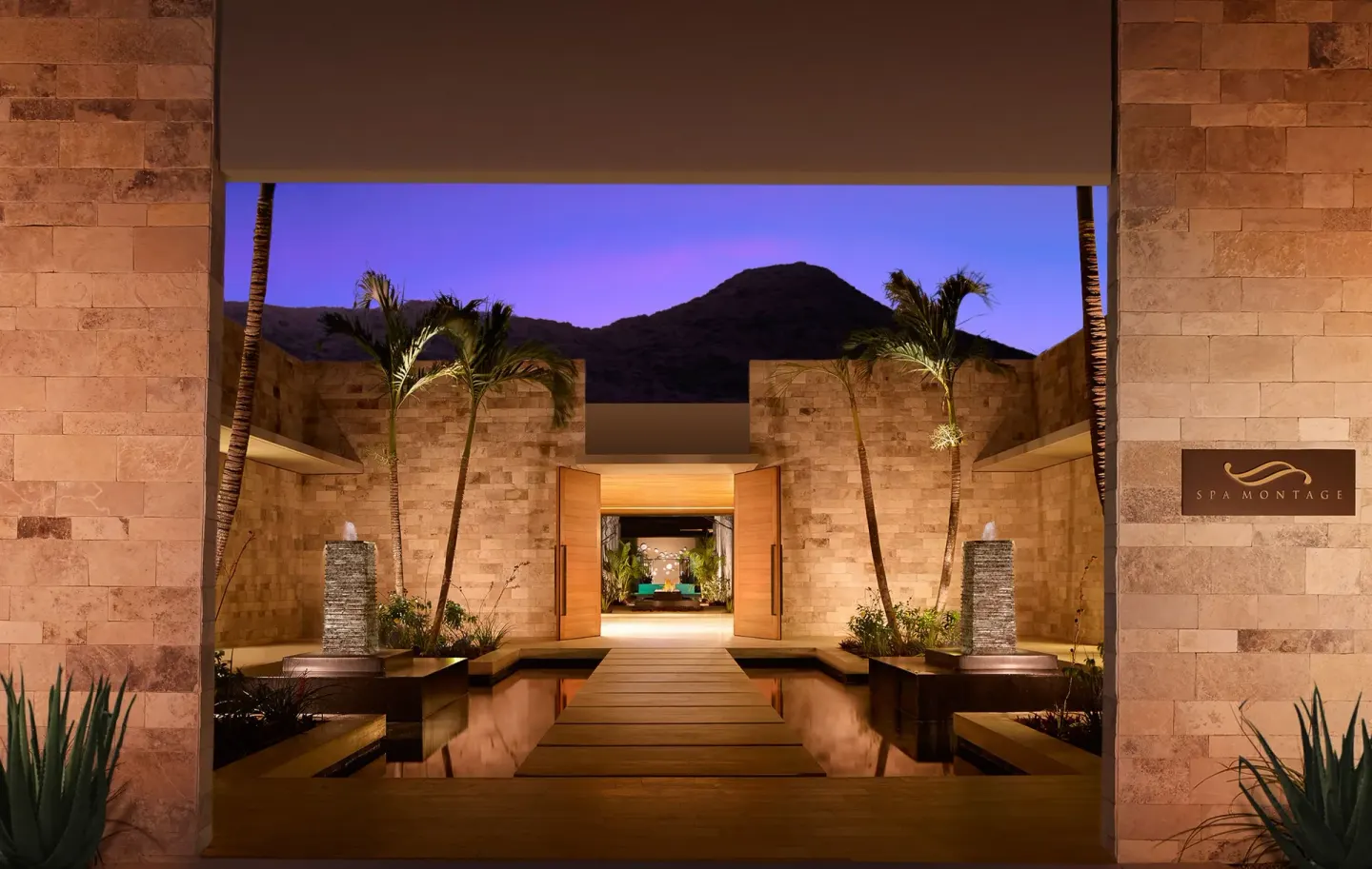 Spa Montage entrance courtyard with palms, reflecting pools, and stone walls at Montage Los Cabos.