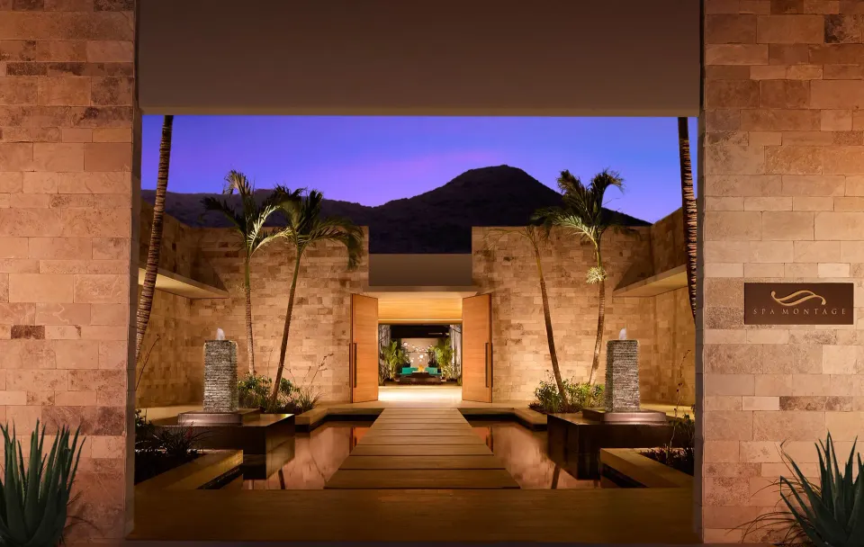 Spa Montage entrance courtyard with palms, reflecting pools, and stone walls at Montage Los Cabos.