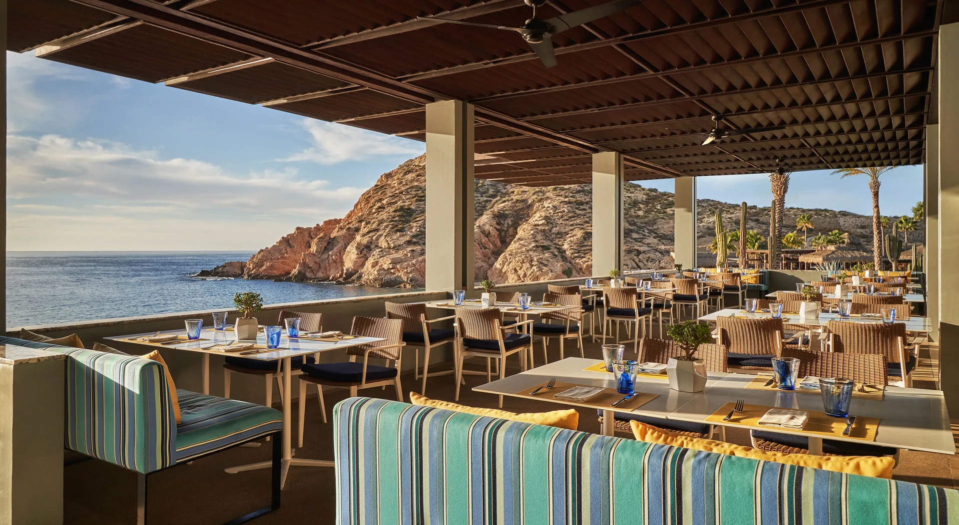 An open-air restaurant terrace overlooks the ocean and rocky cove at Montage Los Cabos.