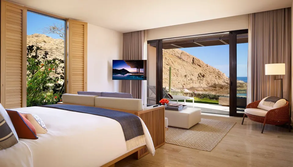 King bed and sitting area in a beach front suite at Montage Los Cabos with rocky shoreline views.