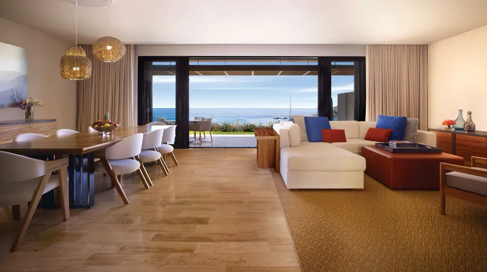 Living and dining room of a beach front suite at Montage Los Cabos with ocean-facing doors.