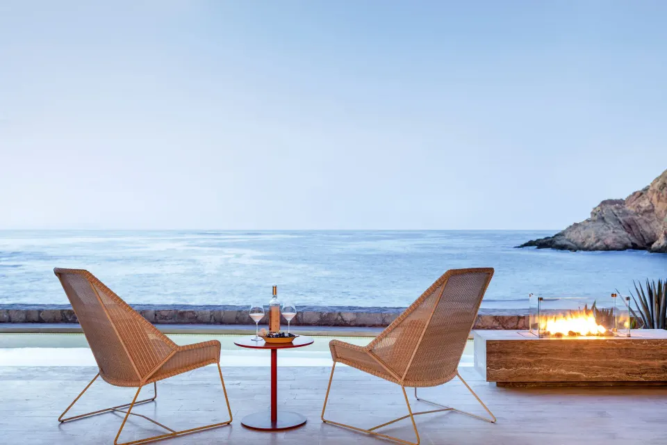 Two terrace chairs by a fire feature facing the sea at Montage Los Cabos.