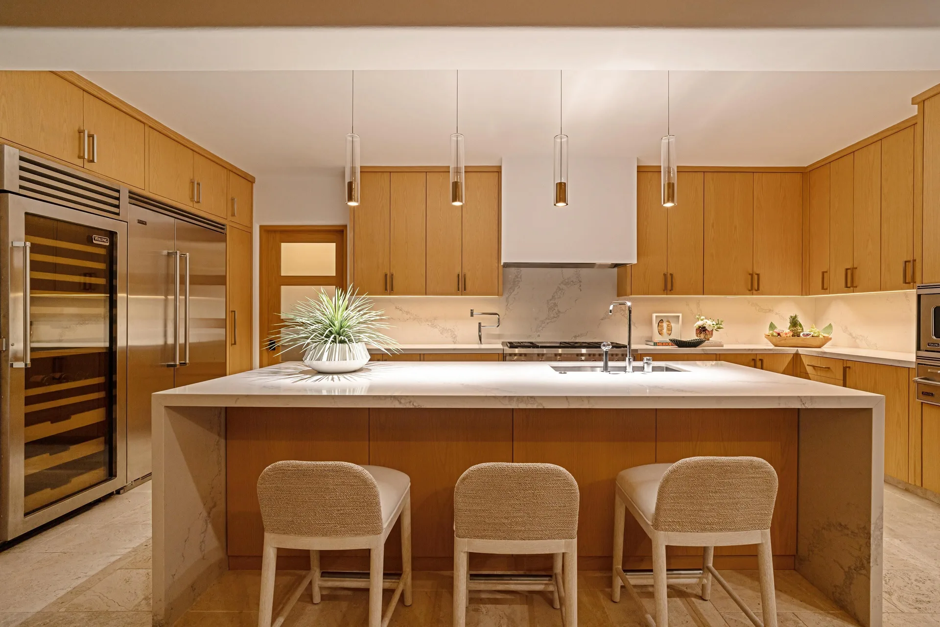 Modern kitchen in Casa Cardon Five Bedroom Home at Montage Los Cabos with island seating and wood cabinets.