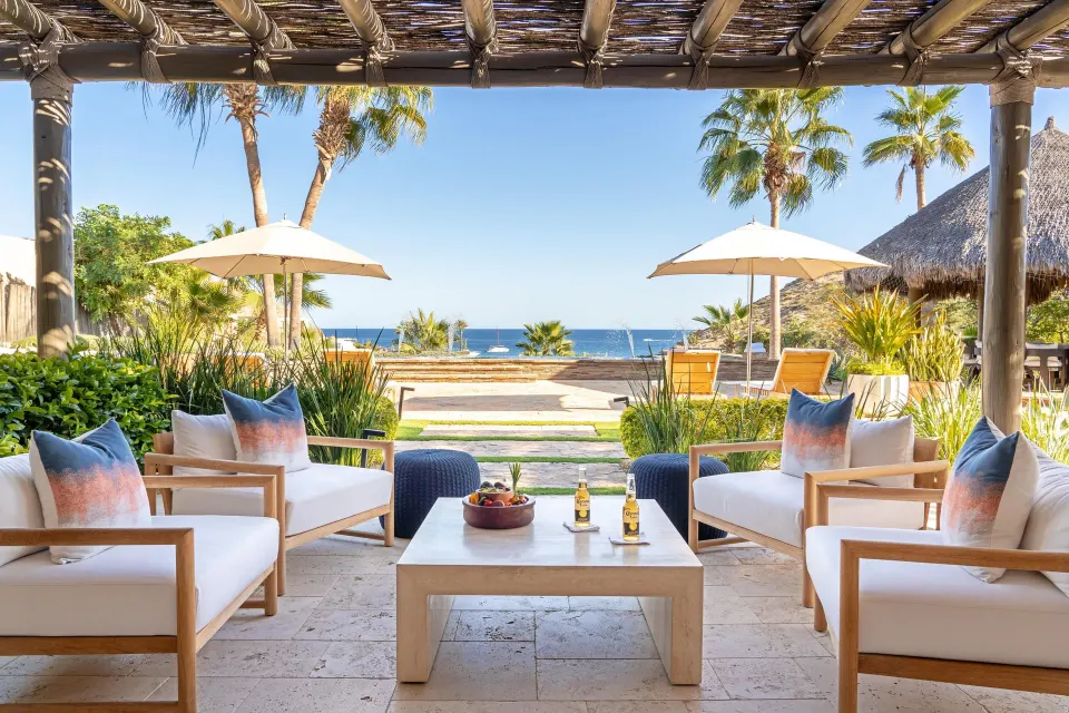 Ocean-facing terrace lounge at Casa Cardon Five Bedroom Home at Montage Los Cabos with umbrellas and palms.