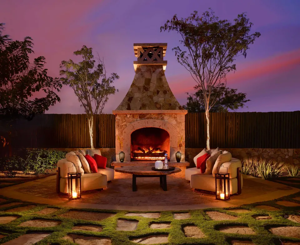 Outdoor fireplace seating area at Casa Cardon Five Bedroom Home at Montage Los Cabos at dusk.