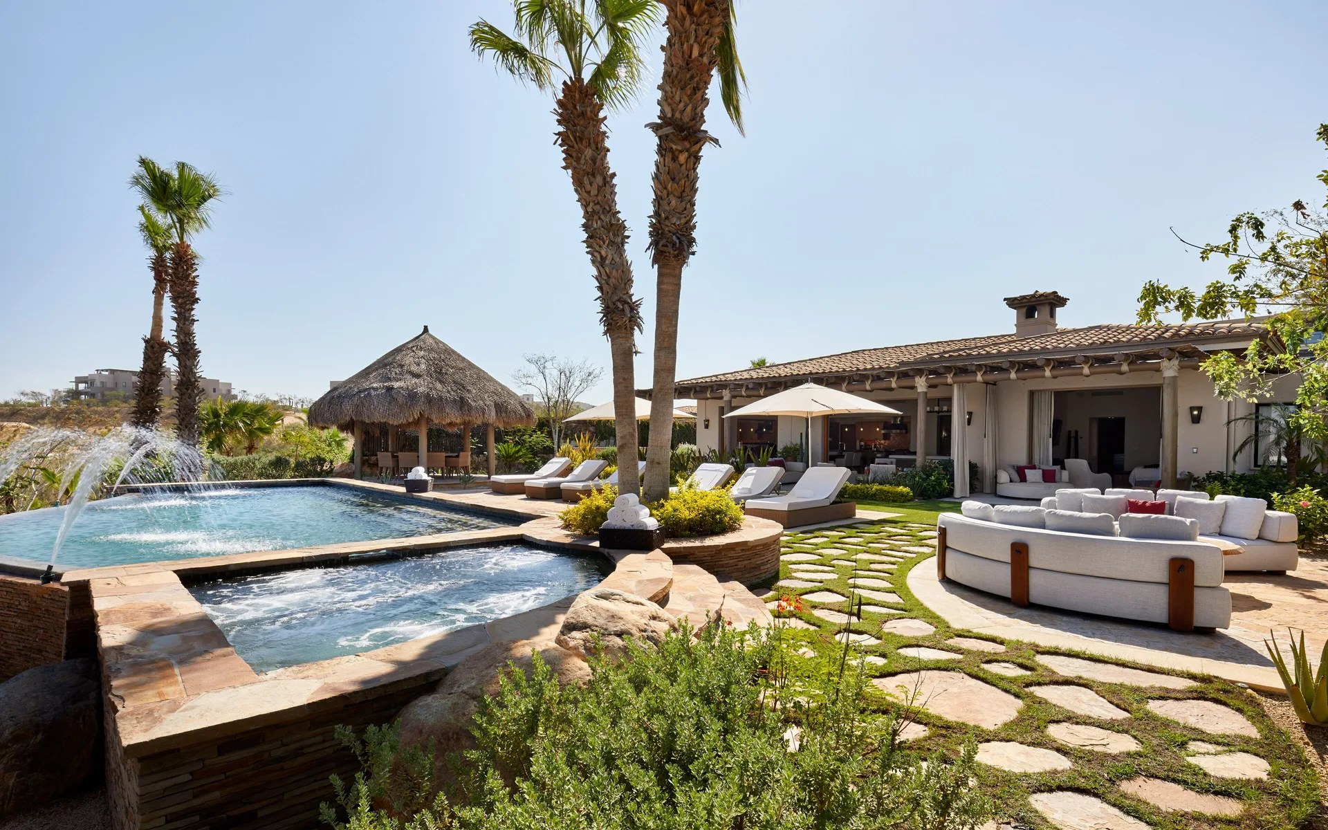 Pool courtyard at Casa Cardon Five Bedroom Home at Montage Los Cabos with palms, loungers, and outdoor seating.