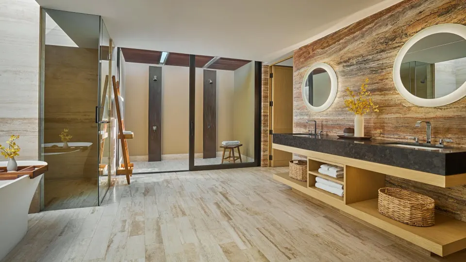 Casa Dolphin bathroom at Montage Los Cabos with double vanity, round mirrors, tub, and showers.