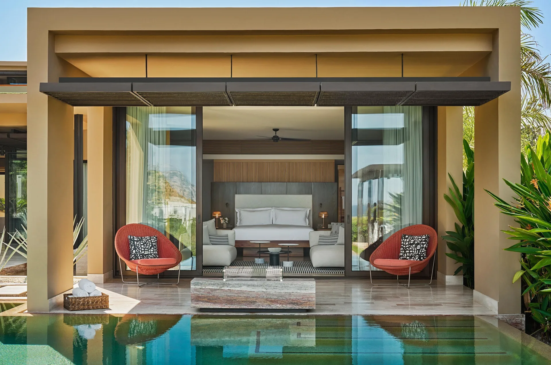 Casa Dolphin bedroom terrace at Montage Los Cabos with king bed, red chairs, and pool edge.