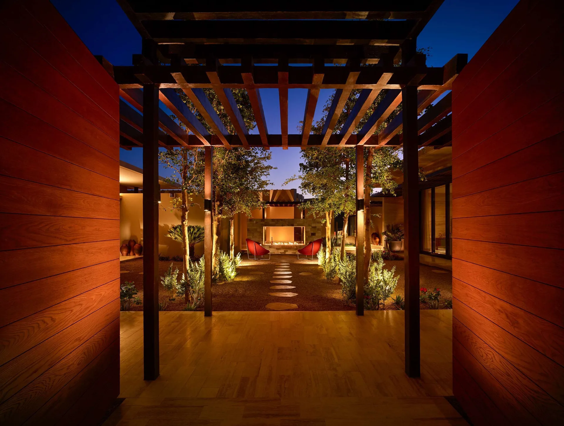 Casa Dolphin courtyard at Montage Los Cabos with pergola, trees, path lights, and seating at night.