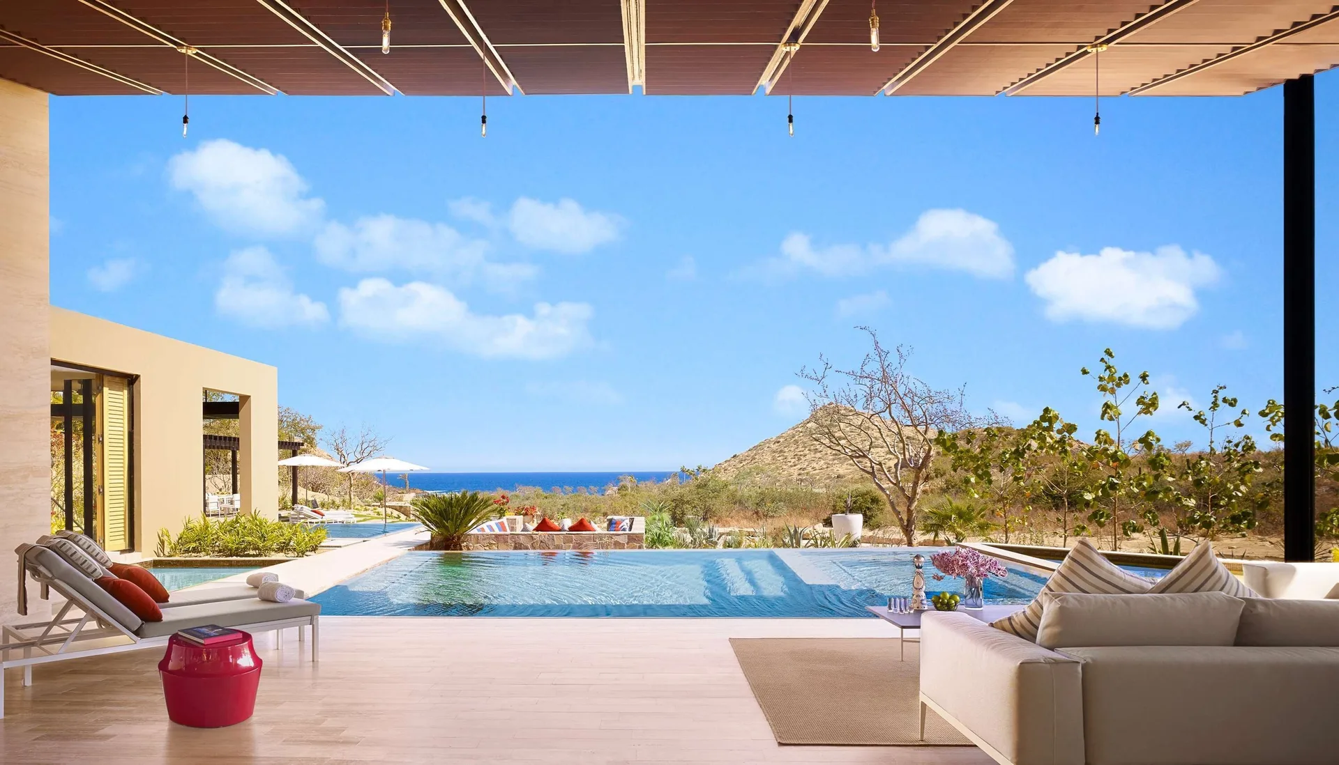 Casa Dolphin covered terrace at Montage Los Cabos overlooking an infinity pool, hillside, and ocean.