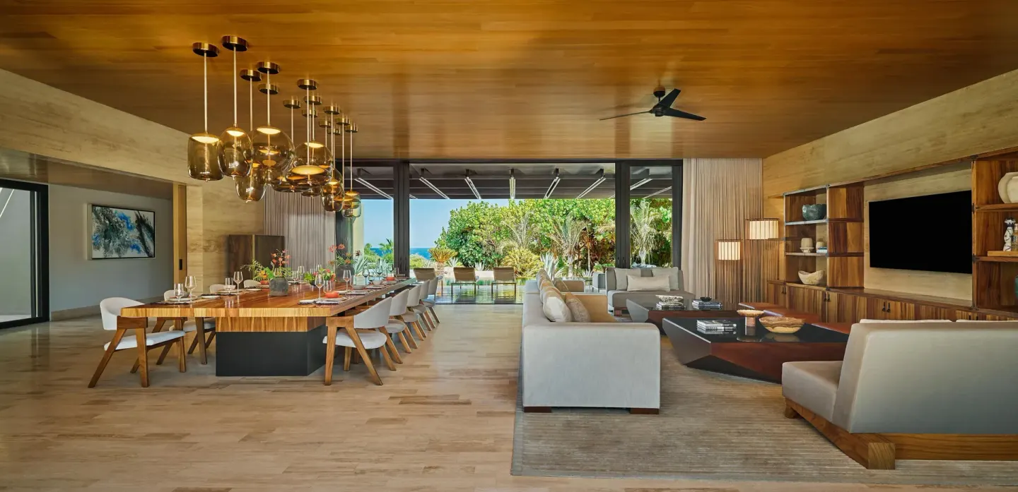 Open living and dining room in Casa Dolphin at Montage Los Cabos with terrace and ocean glimpse.