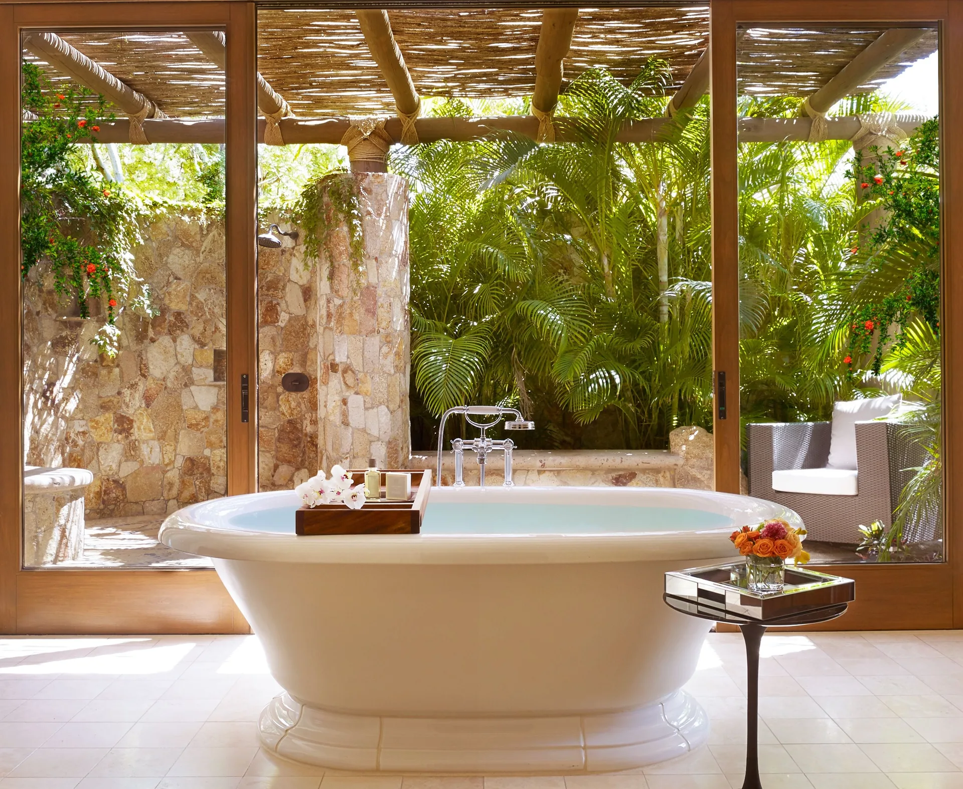 Bathroom tub in Casa Santa Maria at Montage Los Cabos beside glass doors to a garden shower.