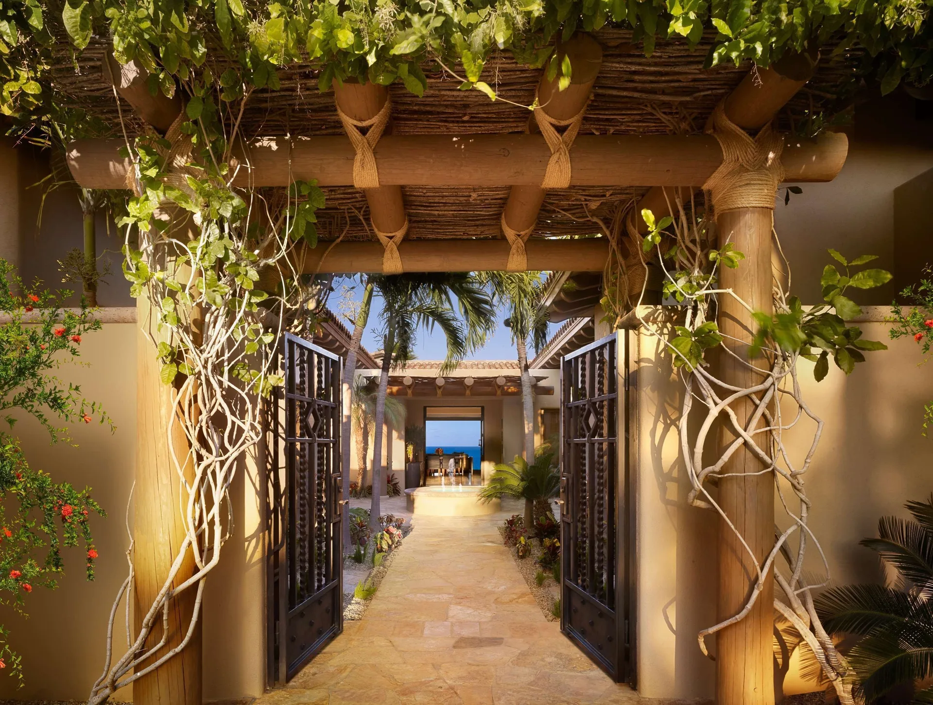 Casa Santa Maria entry gate at Montage Los Cabos with vine-covered pergola and ocean glimpse.