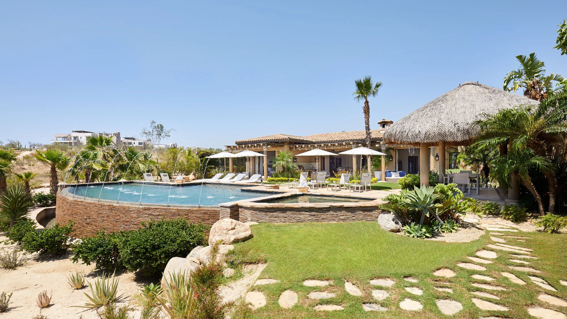 Casa Santa Maria pool, lawn, loungers, and thatched pavilion at Montage Los Cabos.