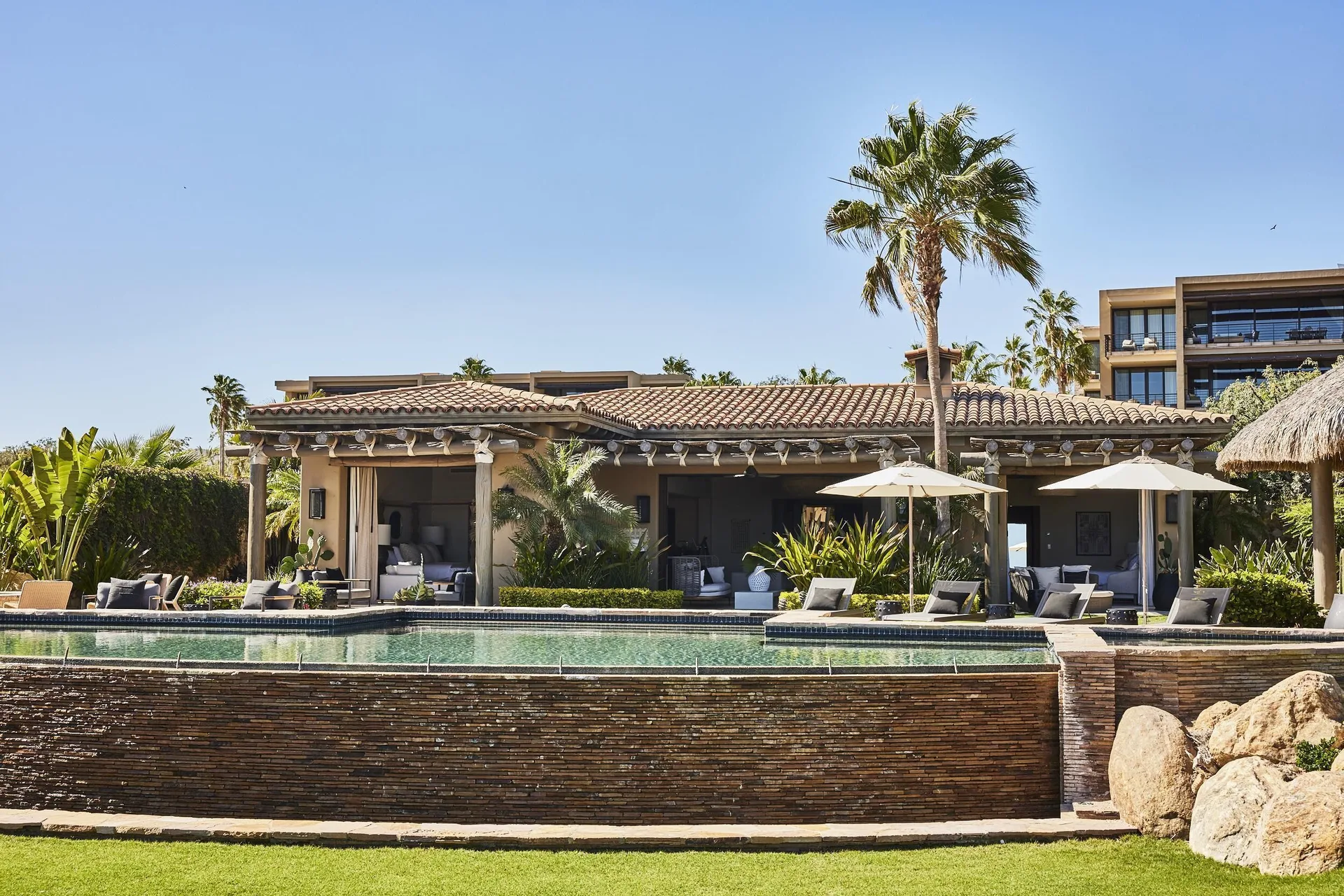 Wide exterior of Casa Santa Maria at Montage Los Cabos with pool, loungers, and lawn.